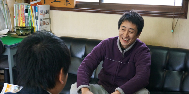 ソファに座り笑顔でインタビューに応じる日下康二さん