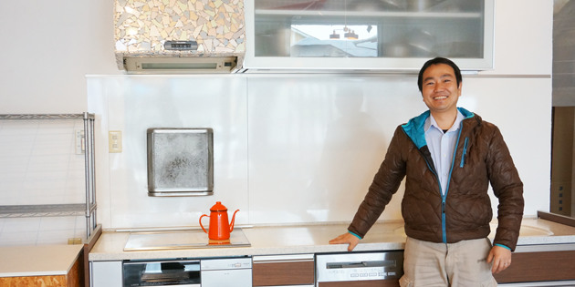 有限会社松永建材店の松永真樹さんがキッチンショールームの前に立っている様子