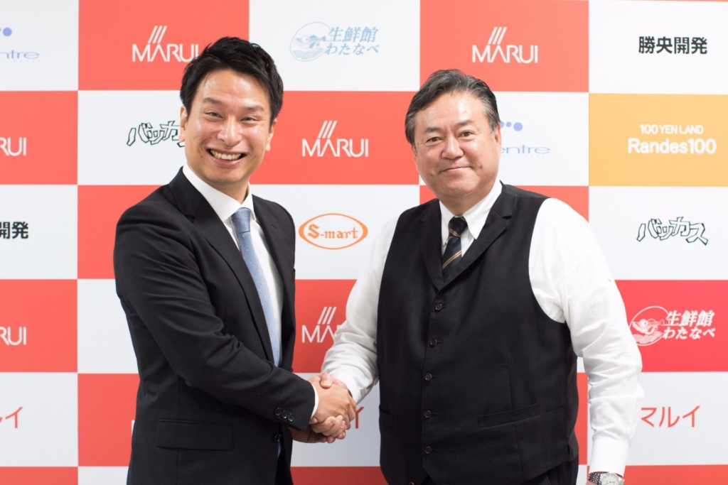 松田欣也さんとインタビュアーが握手をする様子。