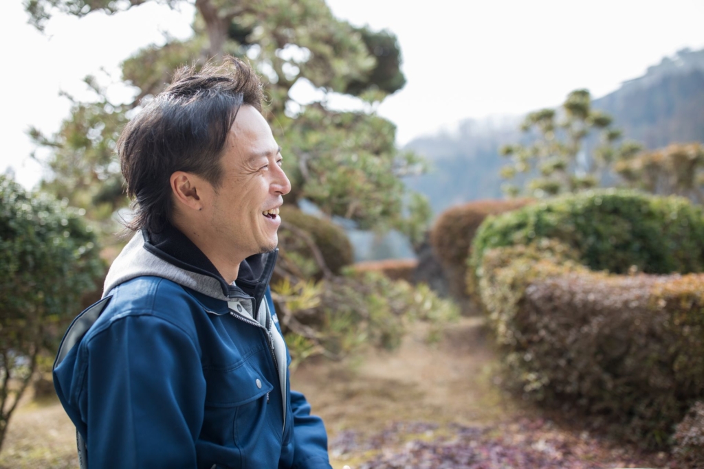 横を向いて微笑む小松隆人氏。
