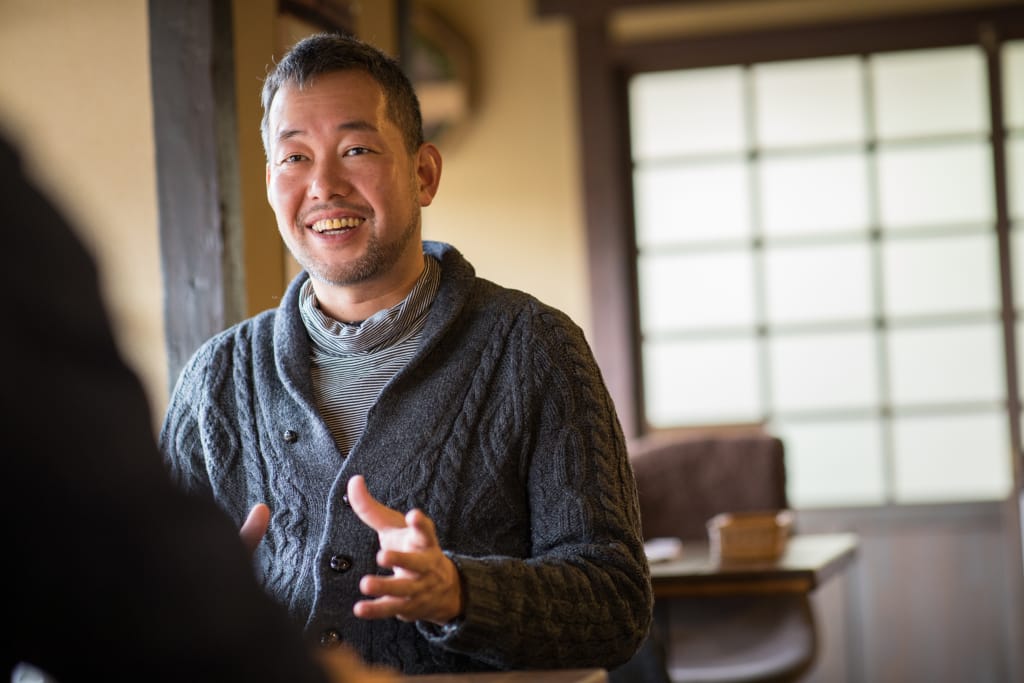 ろまん亭の店内で、笑顔でインタビューに答える松尾さん。