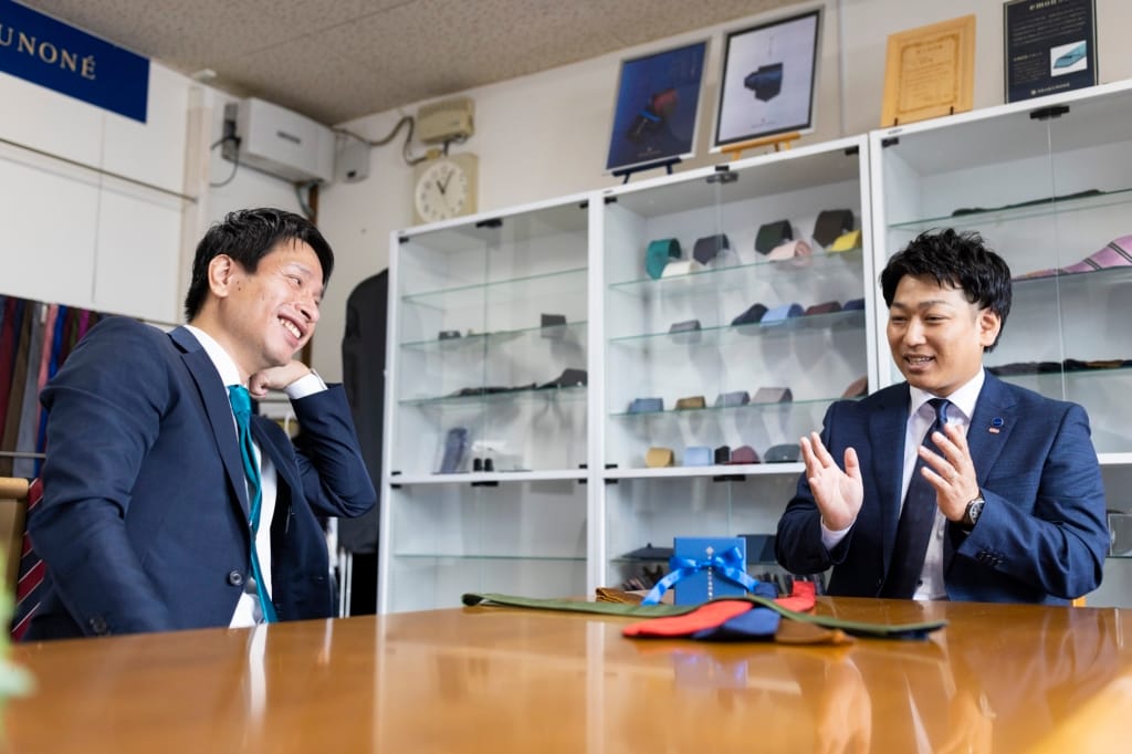 笏本達宏氏とインタビュアーがテーブルを挟んで笑顔で対話している。
