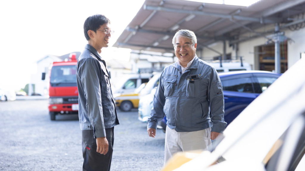 屋外で談笑する岡山電気工事の若手社員とベテラン社員