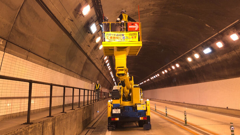 トンネル内で高所作業車を使い照明設備のメンテナンスを行う様子