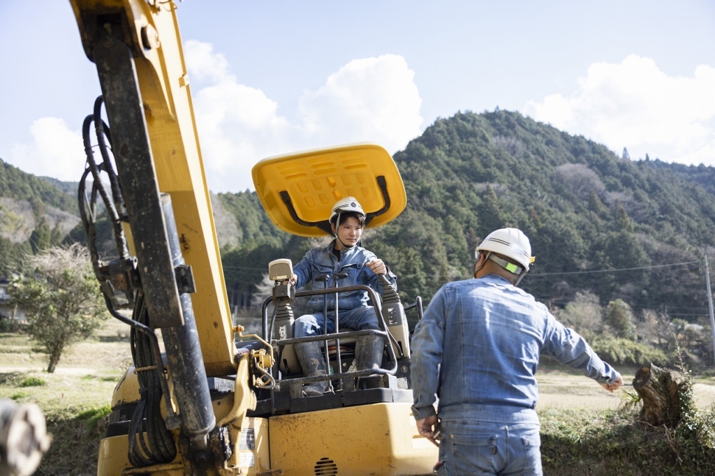 重機に乗った社員が指示を受けている