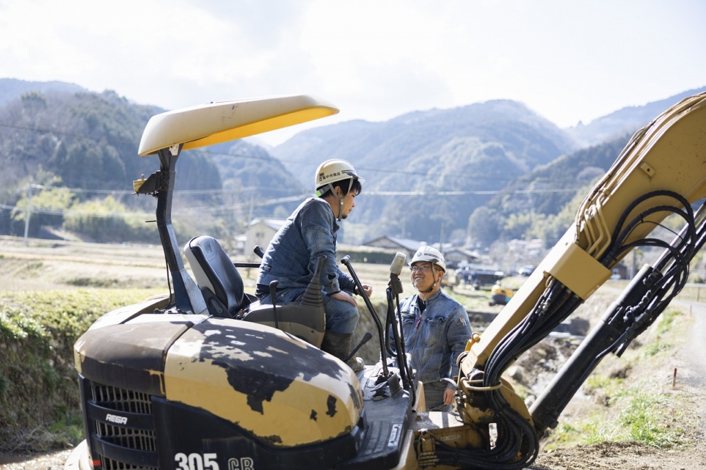 立っている社員と重機に乗っている吉川さんが話している