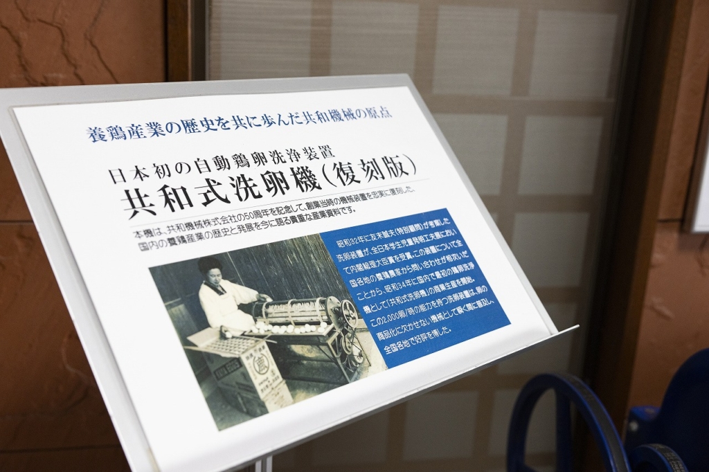 会社のエントランスに展示されている「共和式洗卵機（復刻版）」の説明看板