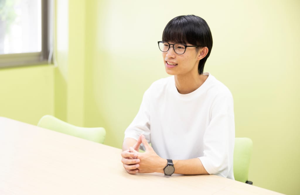 インタビュー中、窓際で手を組みながら話す小津野智葉さん。