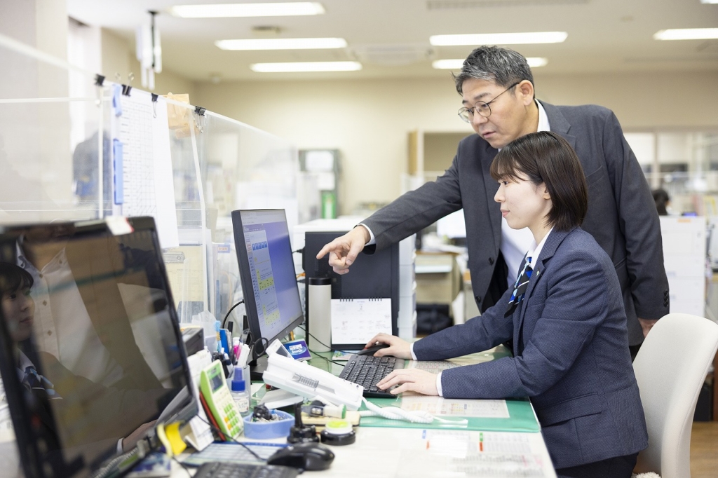 社員が先輩に仕事を教わる様子