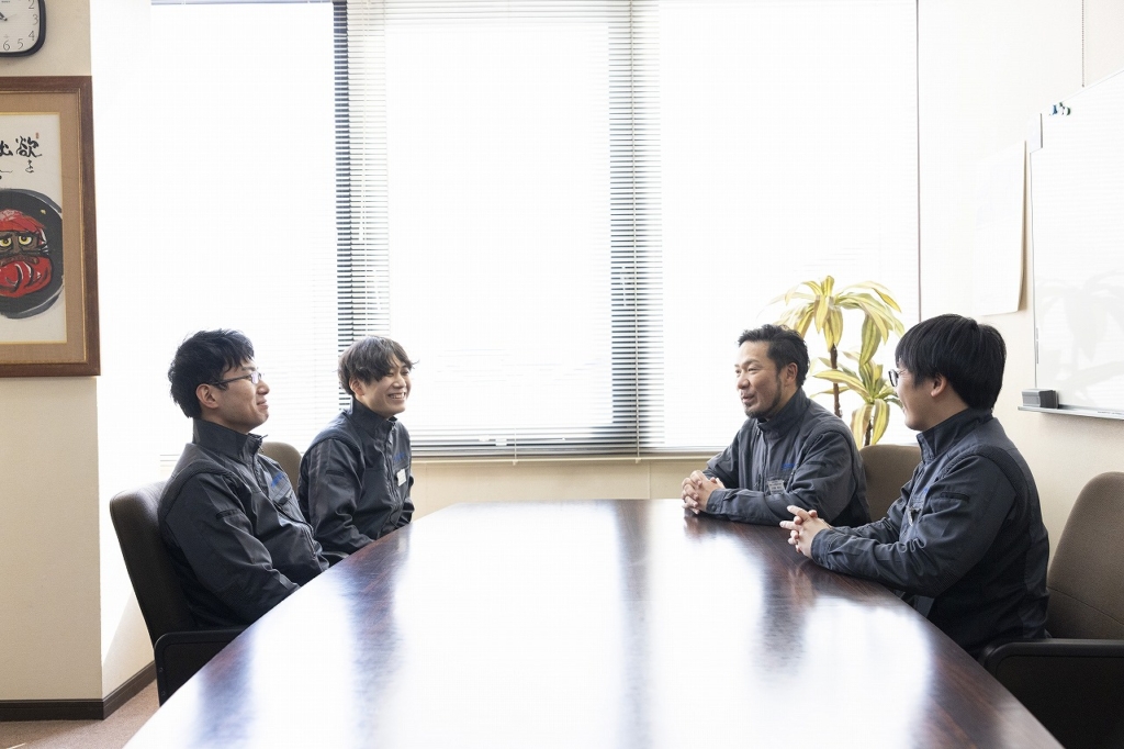 会議室で、社員4名が話し合う様子
