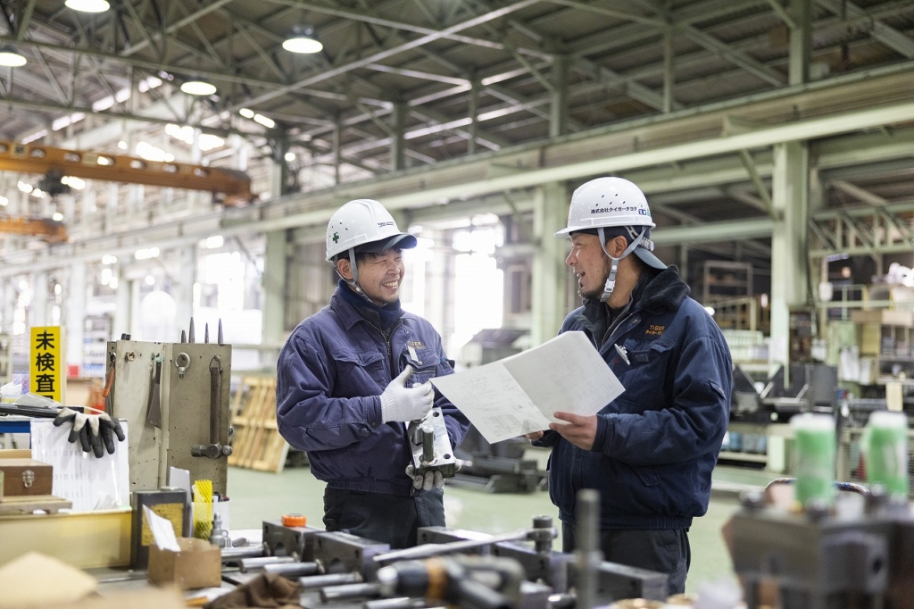 工場内で製品について話し合う2名の社員