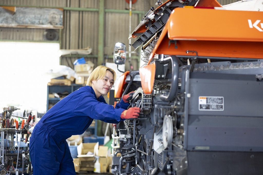 作業服の社員が機械のメンテナンスを行っている様子