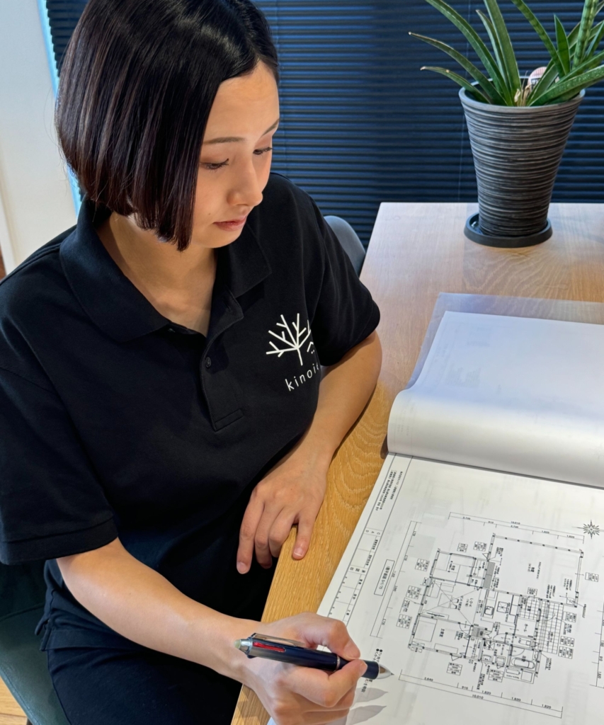 株式会社キノイエの戸田佐緒里さんが、机の上で住宅の設計図面を確認している。