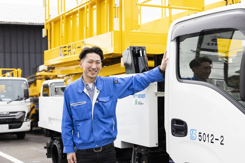 トラックに手をかけ、笑顔を見せる社員