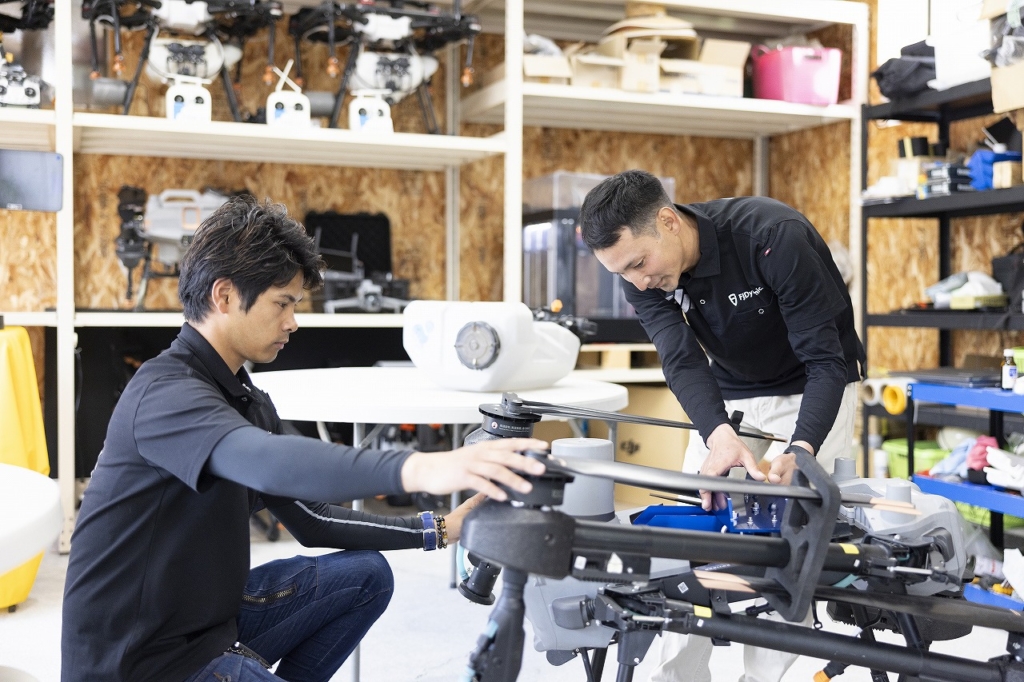 ドローン修理工房で作業する二人の社員
