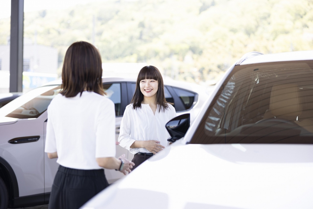 笑顔で展示されているマツダ車の紹介をする廣野さん