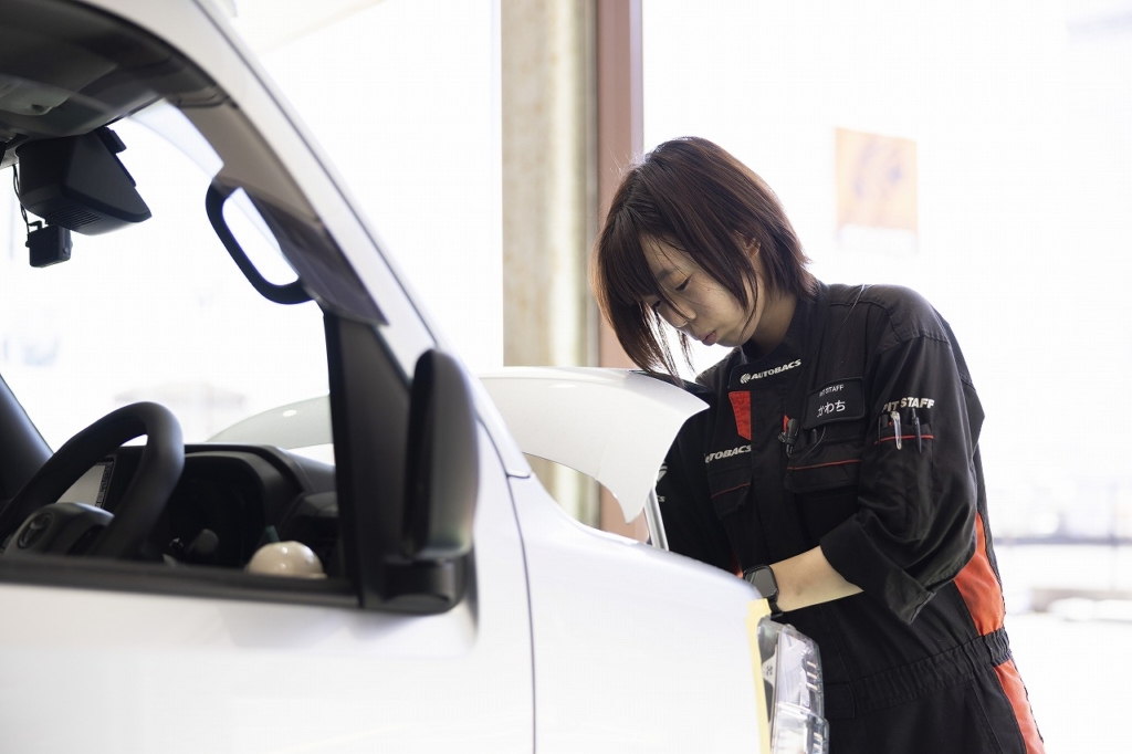 作業服でボンネットを開け整備をする社員