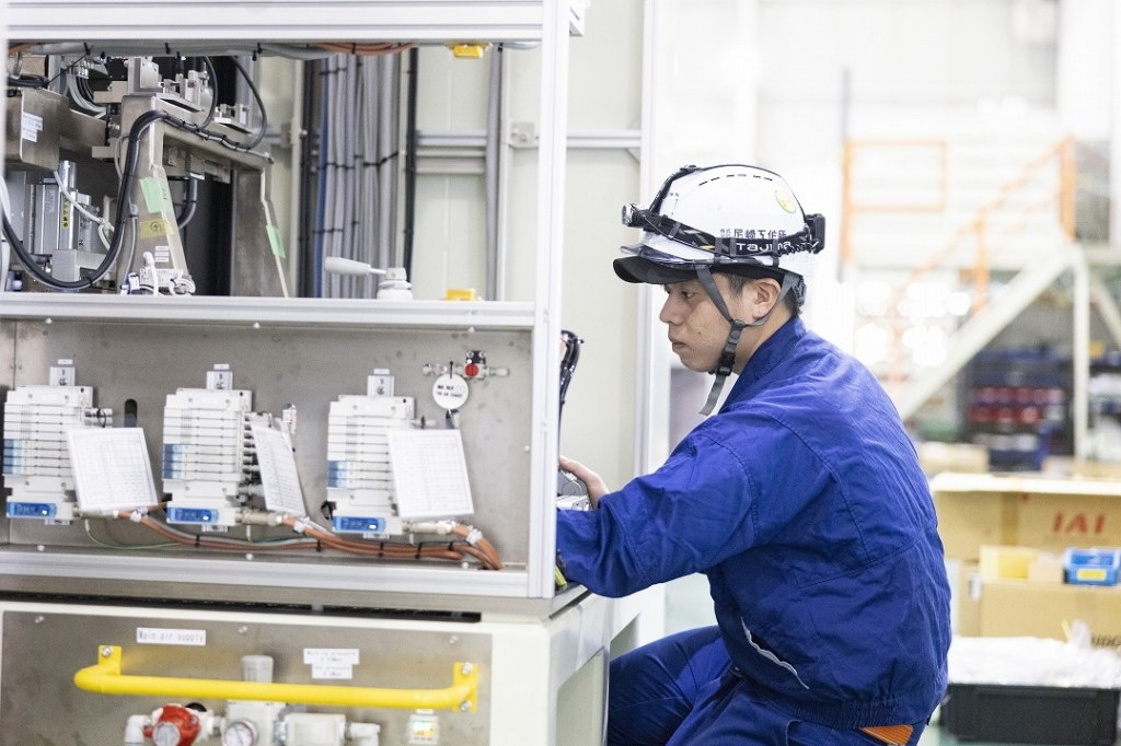 尼﨑工作所の工場で組立を行う写真、製造ラインの調整作業