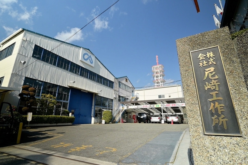 株式会社尼﨑工作所 本社工場とオフィスビル、青空の下の社屋外観