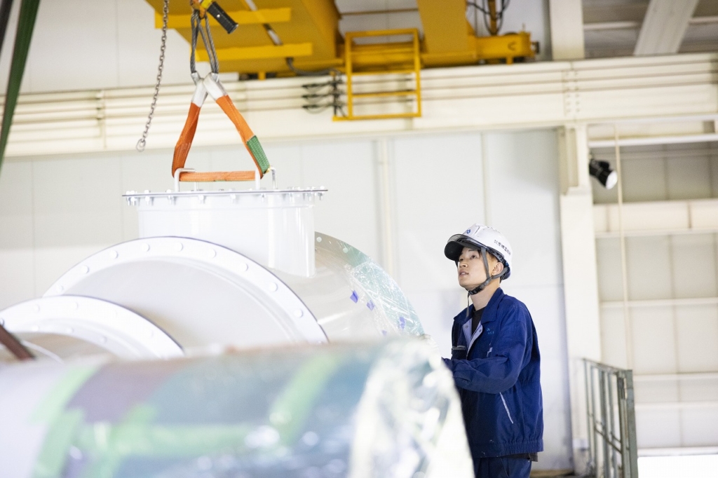 尼﨑工作所の製造ラインでクレーン操作をする工場作業員、大型部品の搬送作業
