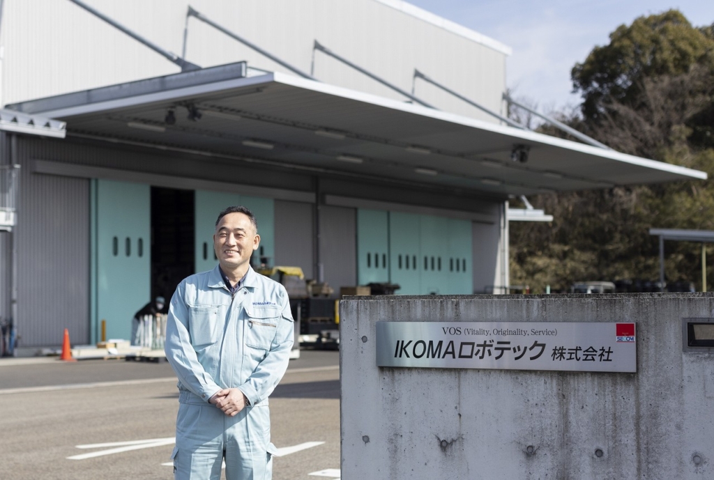 会社の表札横に佇む生駒社長
