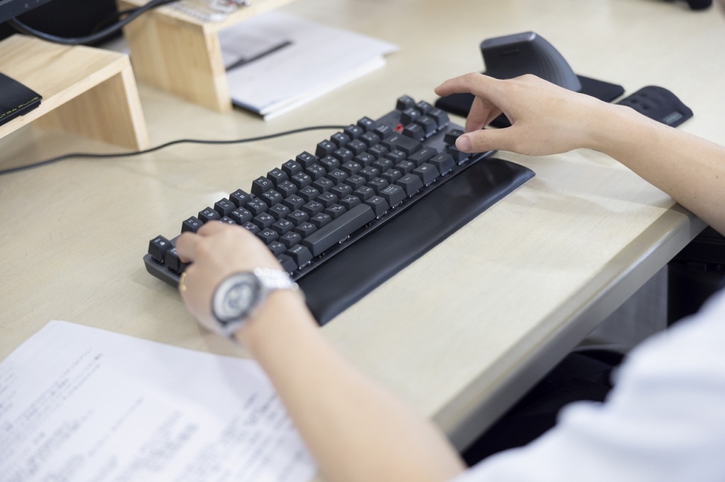 オフィスデスクでキーボードを操作している手元のクローズアップ