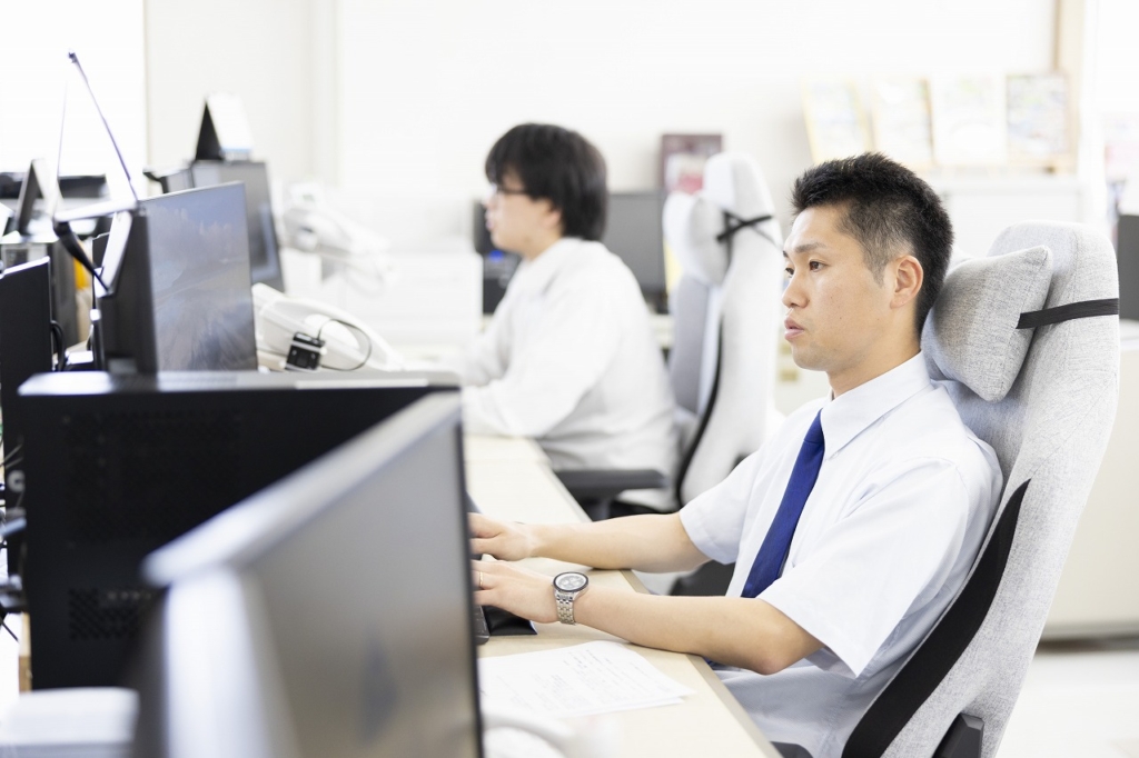 オフィスデスクでコンピューターを操作している男性従業員
