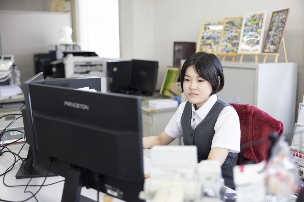 オフィスデスクでコンピューターを操作している若い女性従業員