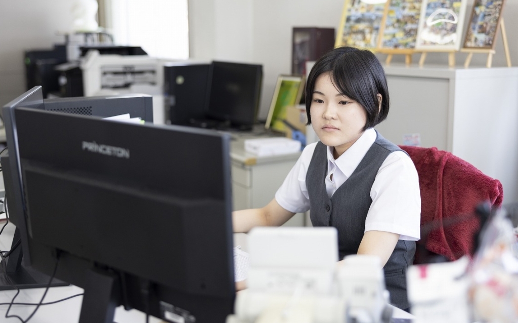 オフィスデスクでコンピューターを操作している若い女性従業員