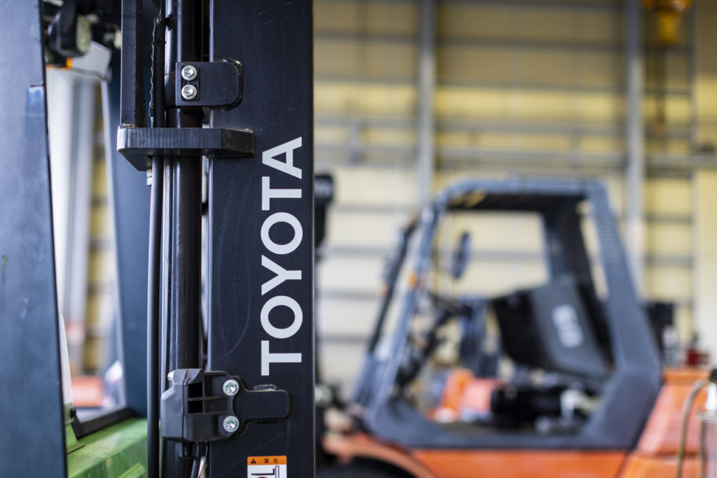 整備工場に置かれたトヨタ製フォークリフトの「TOYOTA」ブランドロゴのクローズアップ。