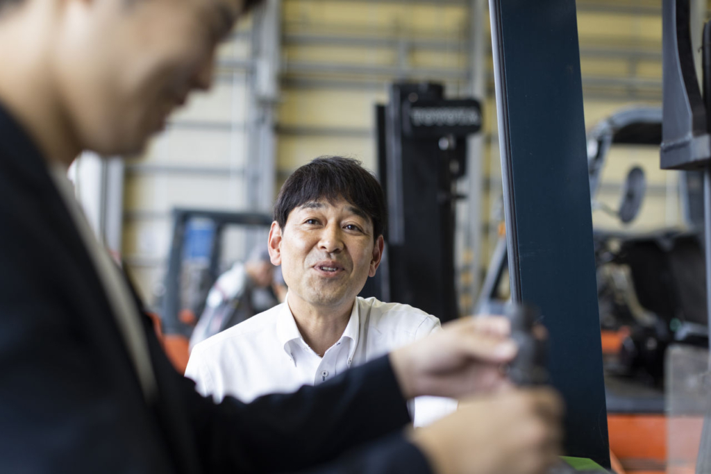 スーツを着用した人とコミュニケーションを取っている北畠所長の様子。