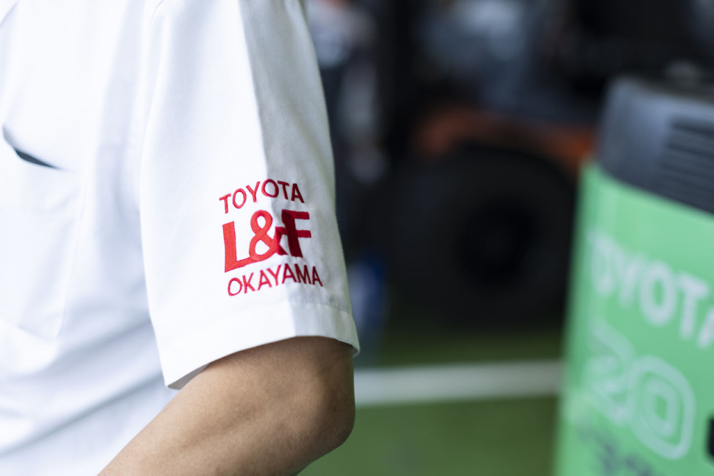 トヨタL&F岡山のスタッフが着用する白いユニフォームの袖にある「TOYOTA L&F OKAYAMA」のロゴのクローズアップ。