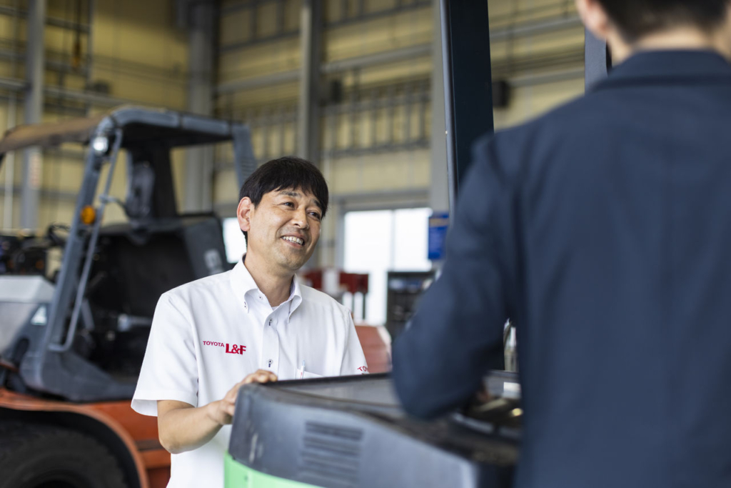 トヨタL&F岡山の工場内で、北畠所長とスーツを着用した人が話し合いをしている様子。