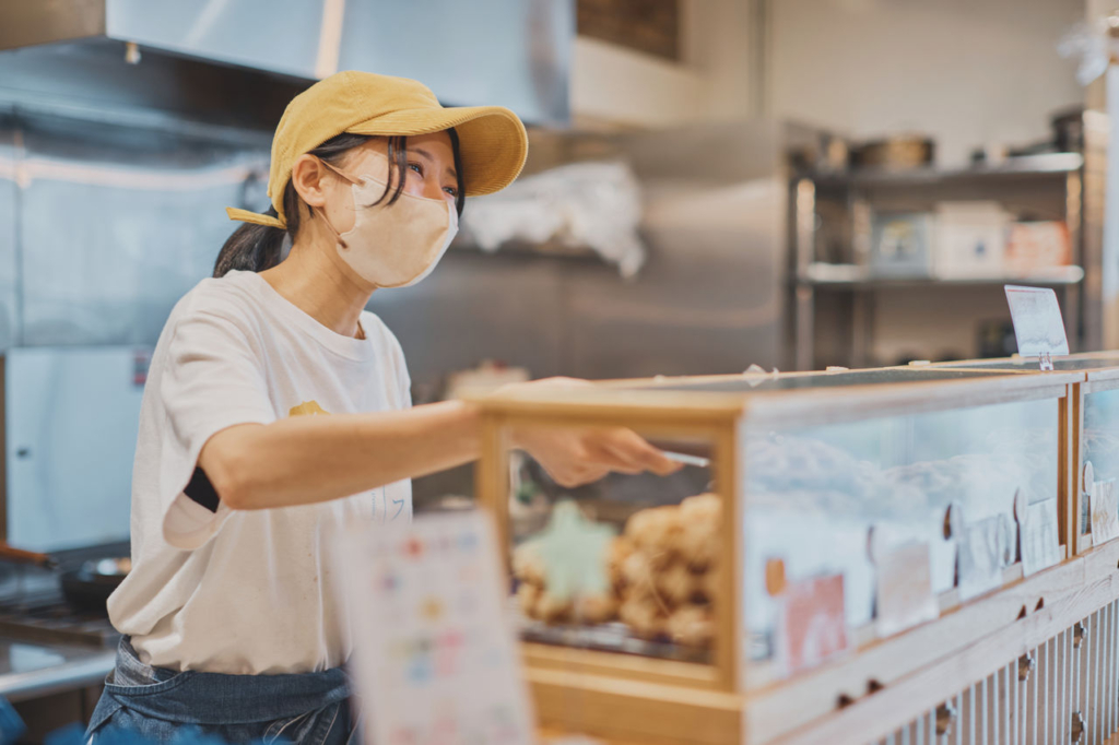 女性スタッフがワッフルの並んだショーケースを準備している横からのショット。
