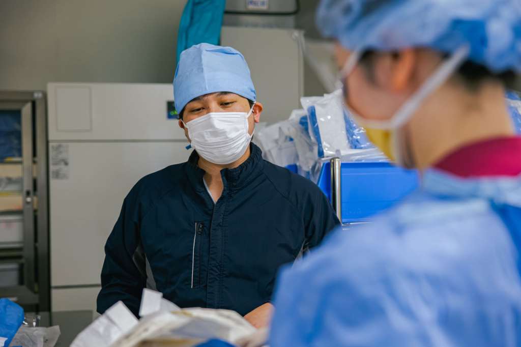 手術用のキャップとマスクを着用した男性医師が手術室に立っている。