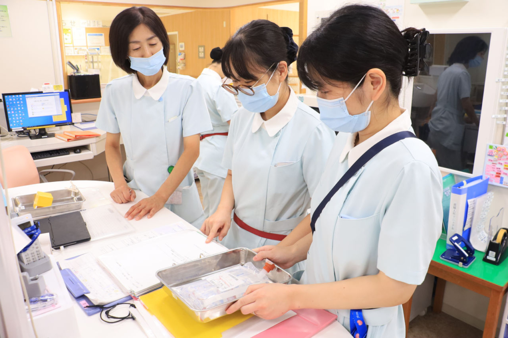3人の助産師がナースステーションでカルテや医療器具を確認している。