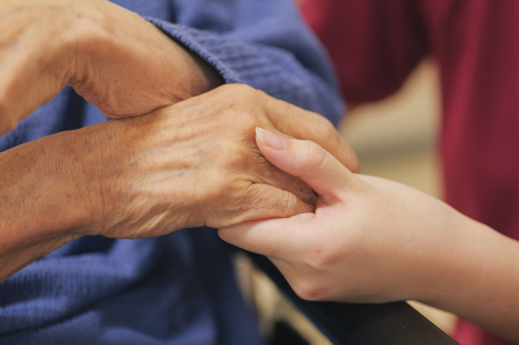 介護職員が利用者の手を優しく握る様子
