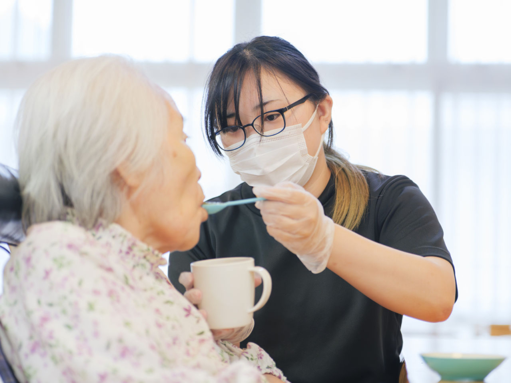 介護職員が利用者の食事をサポートしている様子