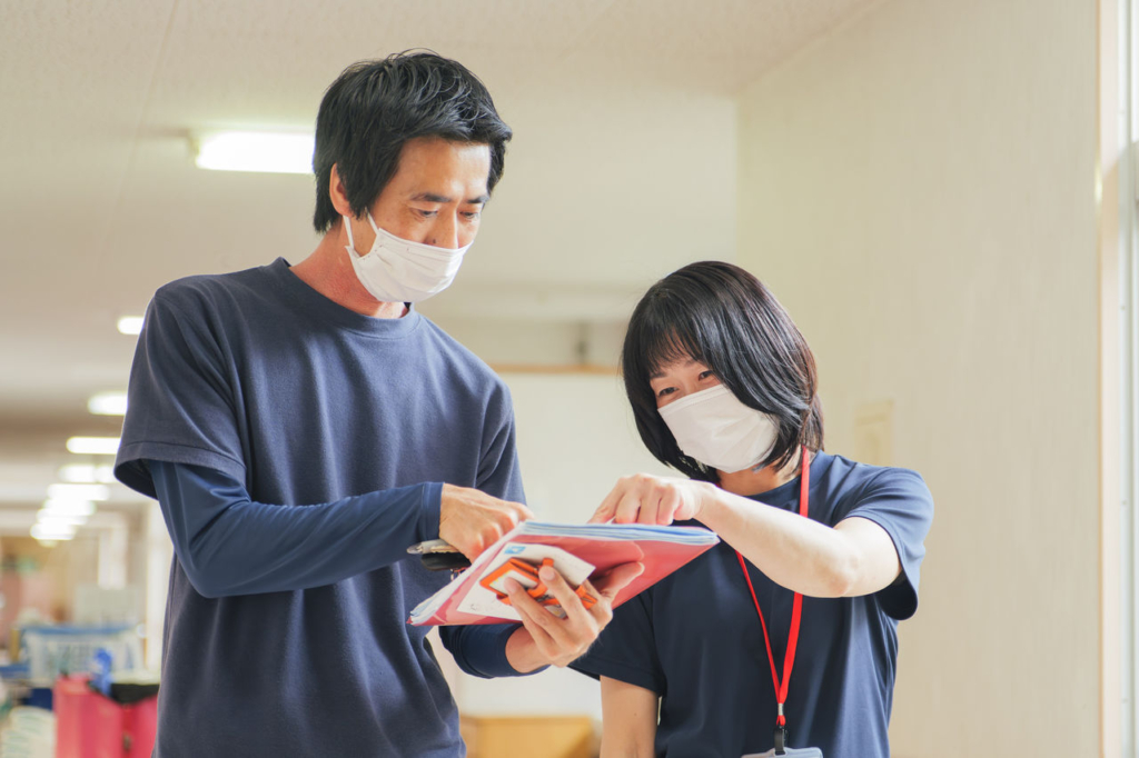 「白寿荘」の職員が廊下で情報共有している様子