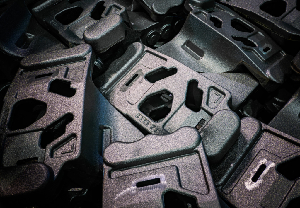 黒く塗装された複雑な形状の鋳造自動車部品の山