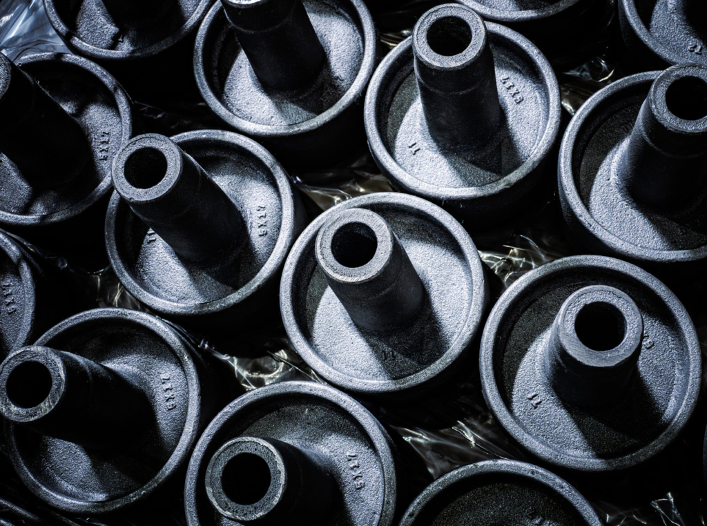 ビニールの上に整然と並べられた、円筒状の突起がある黒い鋳造製品