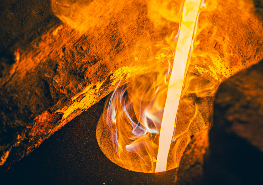 砂型の注ぎ口に、赤熱した溶けた鉄が流し込まれている様子