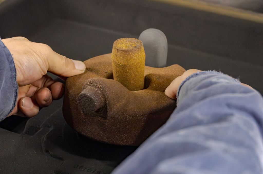 茶色の砂型に円筒形の中子を手作業でセットしている様子