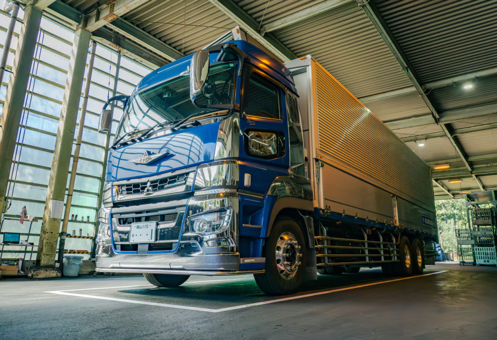 工場の屋根のある出荷場に停車している青い大型トラック