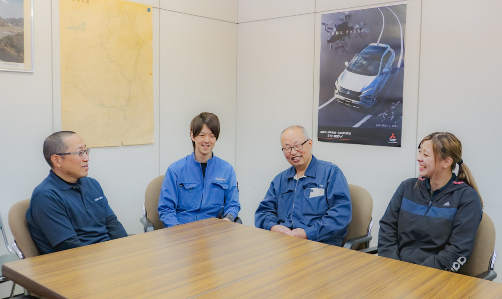 会議室のテーブルを囲み、リラックスした様子で話をしている4名の社員