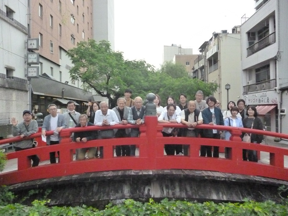 社員旅行先の赤い橋の上で撮影された集合写真