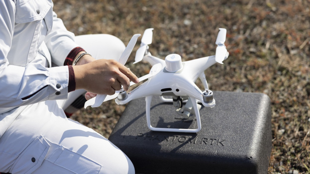 地面に置かれたドローンのプロペラ付近を調整している手元
