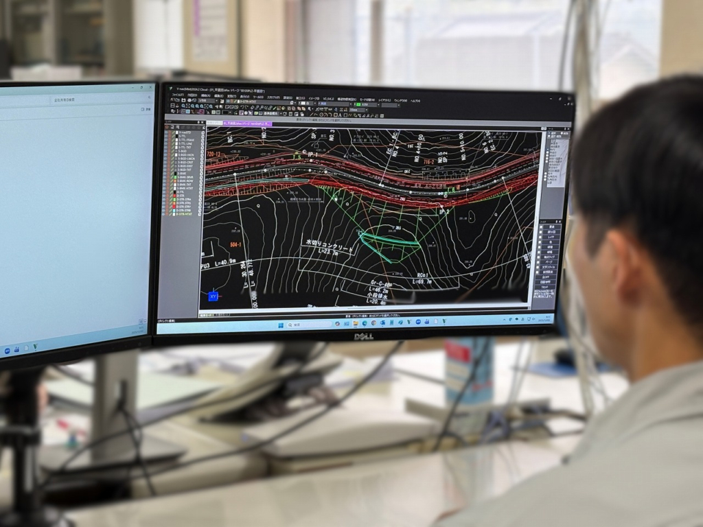 デュアルモニターを使用し、CADソフトで図面を作成している男性