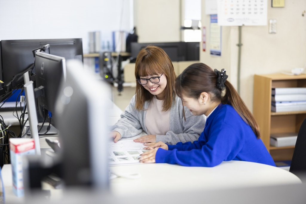 デスクで図面や資料を一緒に確認し、笑顔で話す清友さんと田淵さん