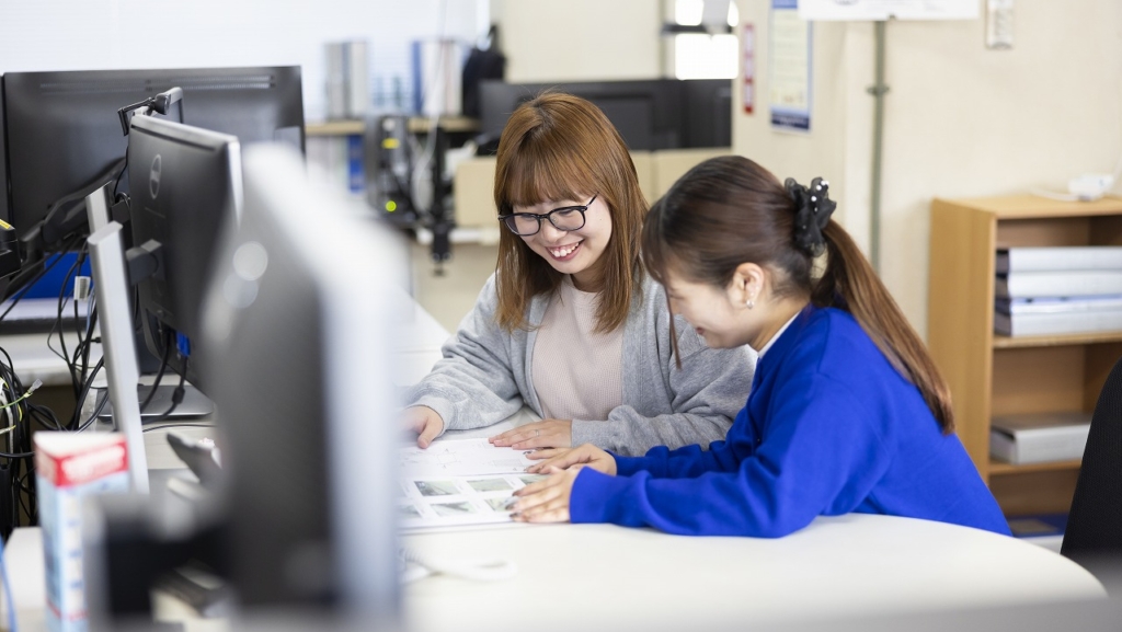 デスクで図面や資料を一緒に確認し、笑顔で話す清友さんと田淵さん